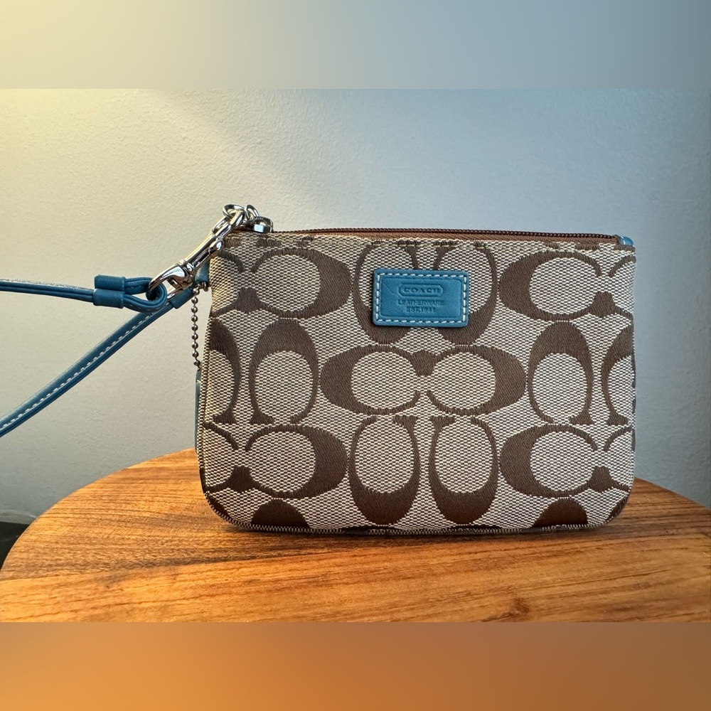 Tan Coach wristlet in Signature Canvas with teal trim and strap